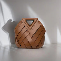 Brown woven leather handbag with triangle handle on white minimalist background