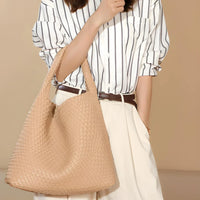 Woman in striped blouse with beige woven tote bag and cream pleated skirt