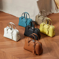 Six leather handbags in assorted colors on herringbone wood floor