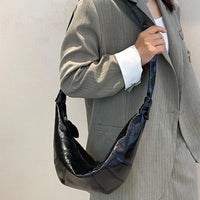 Woman in gray blazer carrying black crescent shoulder bag