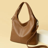 Brown leather tote bag with shoulder strap on beige background, stylish handbag accessory