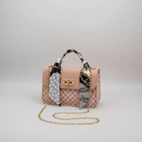 Designer handbag with patterned scarf and gold chain on a decorative surface