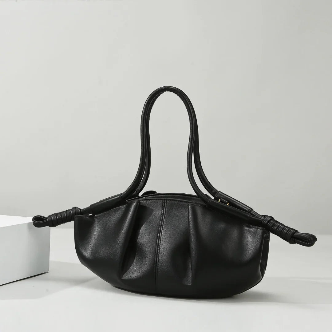 Black leather handbag with ruched design and double handles on a white background