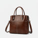 Brown leather handbag with white stitching, top handles, and detachable shoulder strap