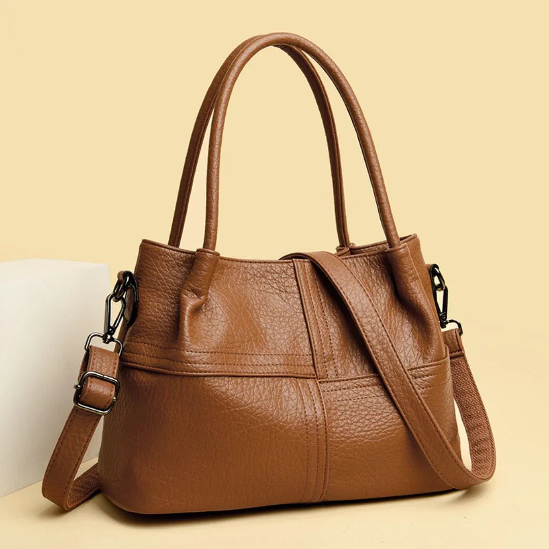 Brown leather handbag with shoulder strap on beige background, stylish women's purse
