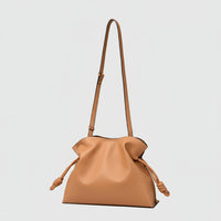Tan leather knot bag with adjustable shoulder strap, minimalist purse on white background