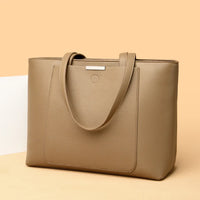 Taupe leather tote bag with front pocket and handles on beige background