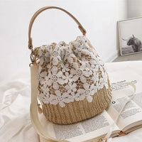 Straw crochet bucket bag with white floral lace, displayed on a bed with an open magazine.