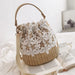 Straw crochet bucket bag with white floral lace, displayed on a bed with an open magazine.