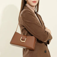 Woman in brown blazer with brown leather shoulder bag and gold hardware