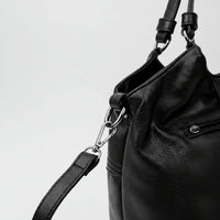 Black leather handbag with silver zipper and detachable strap on white background