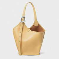 Yellow leather bucket bag with adjustable strap and silver buckle on white background