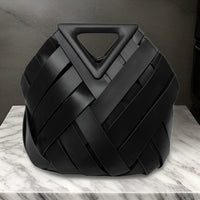 Black woven leather handbag with triangle handle on marble surface