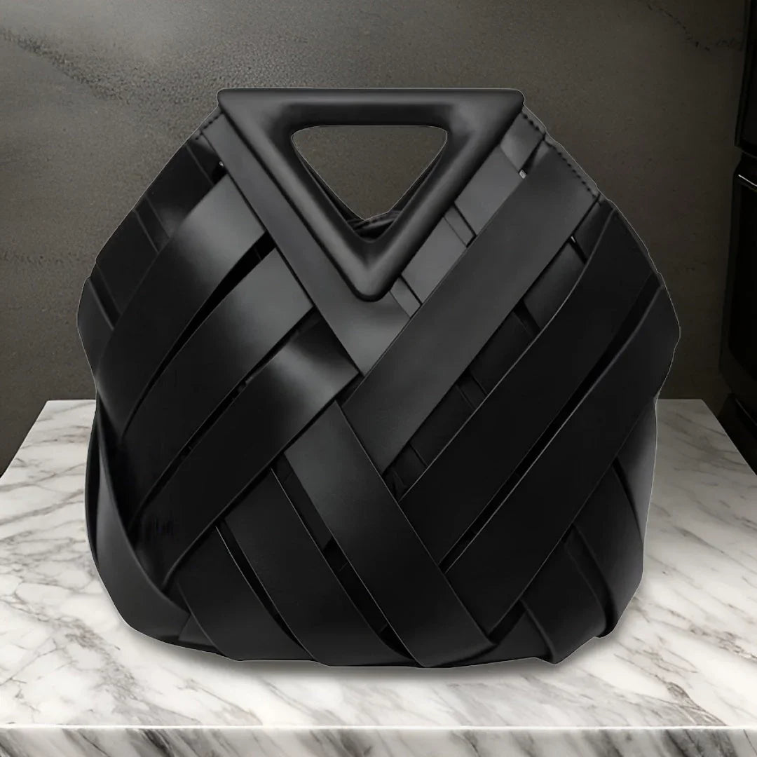 Black woven leather handbag with triangle handle on marble surface