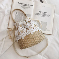 Woven straw bag with white floral lace detail on white fabric beside an open art book