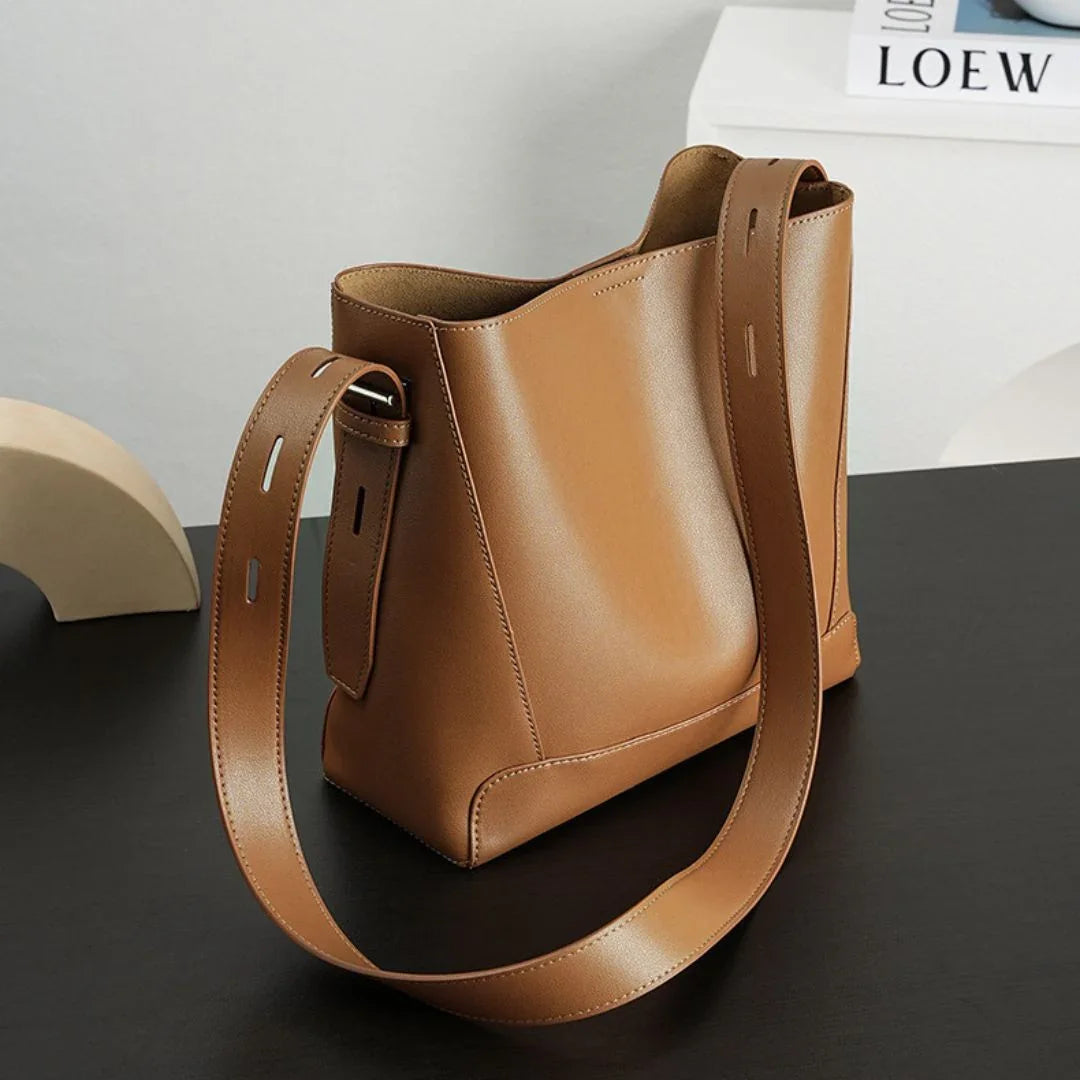Minimalist brown leather shoulder bag on black desk, modern decor, fashion accessory