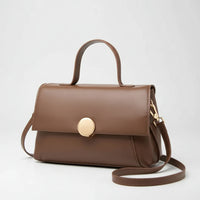 Brown leather handbag with top handle, gold clasp, and shoulder strap on white background
