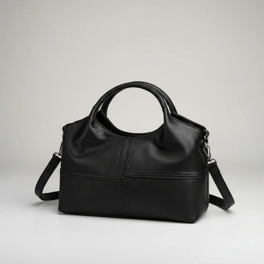 Black leather handbag with round handles and detachable shoulder strap on a white background