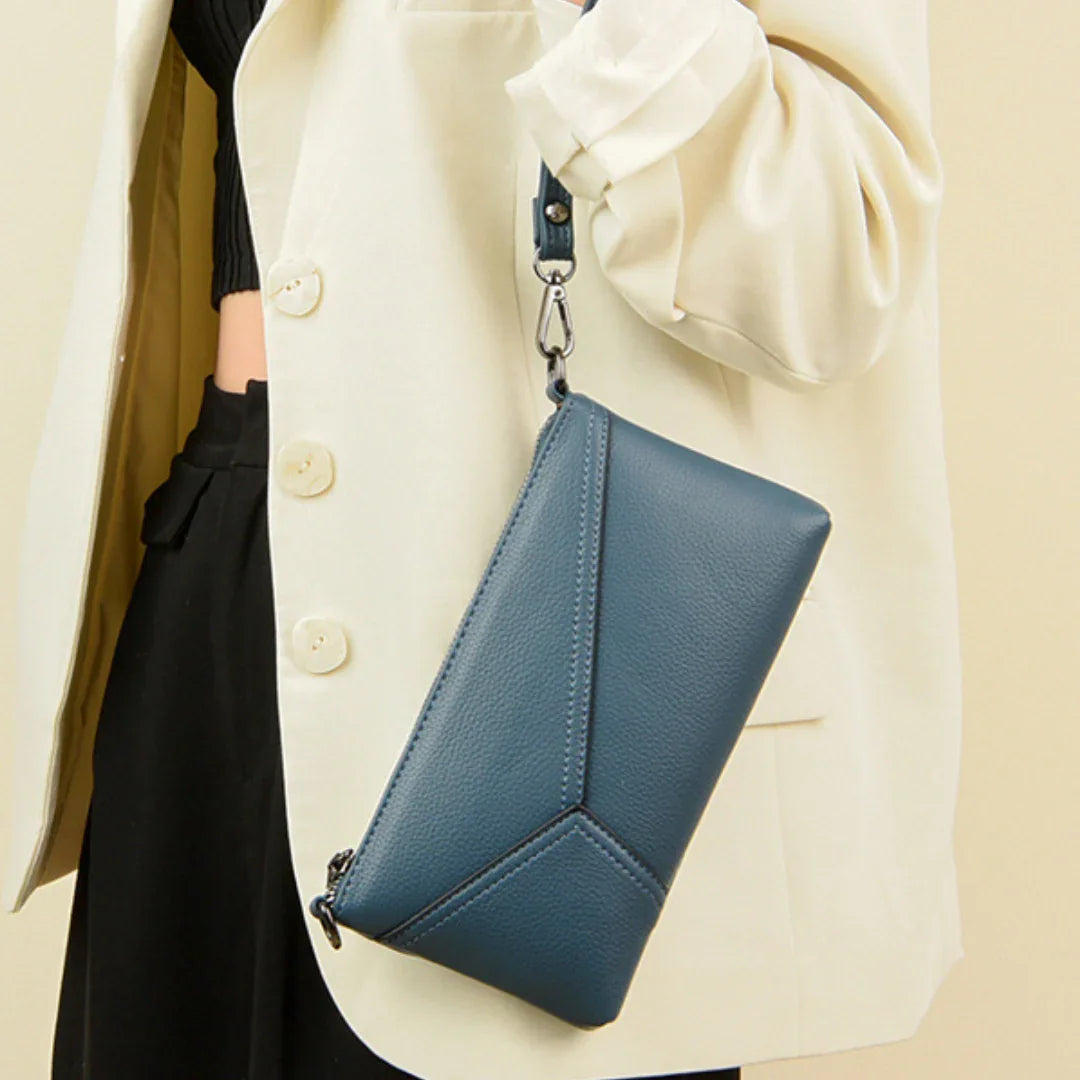 Woman in cream blazer holding blue leather wristlet clutch bag