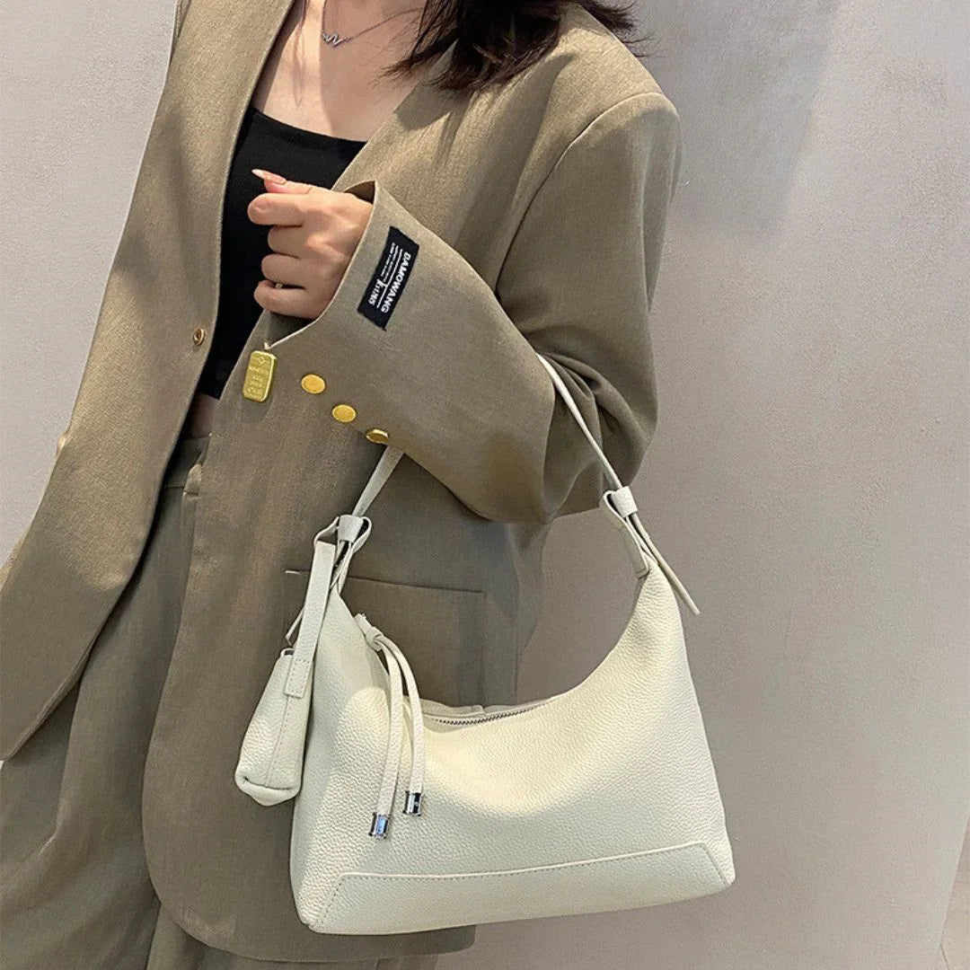 Woman in tan blazer holding white leather shoulder bag, chic fashion accessory style
