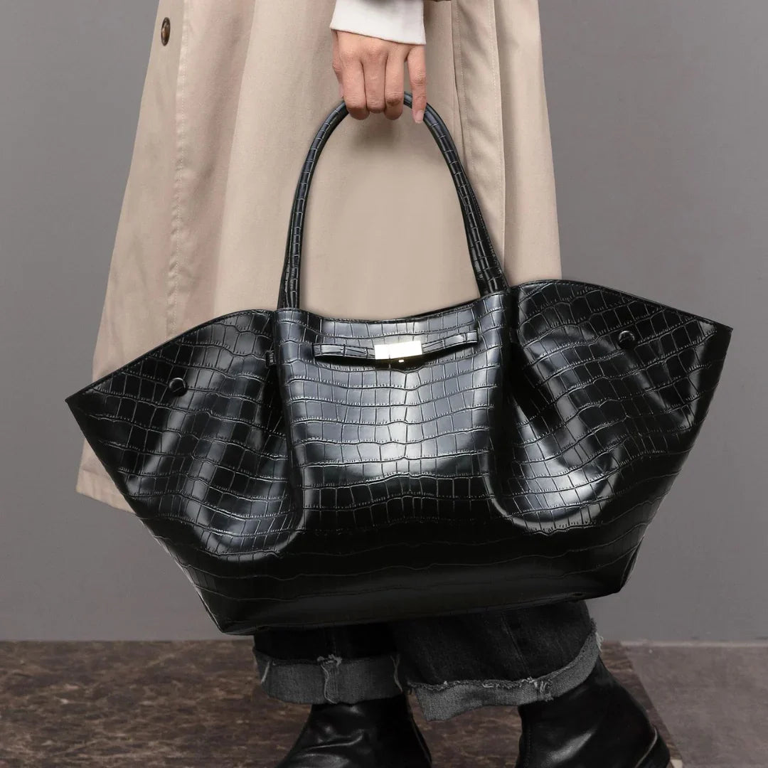 Woman holding large black crocodile-embossed leather tote bag, stylish fall fashion