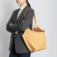 Woman in grey blazer carrying large yellow leather tote bag