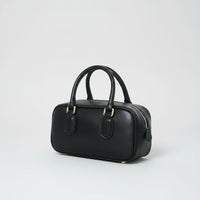 Black leather handbag with gold hardware and double handles on a white background