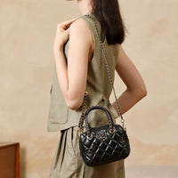 Woman in beige sleeveless dress carrying a black quilted leather handbag with chain strap