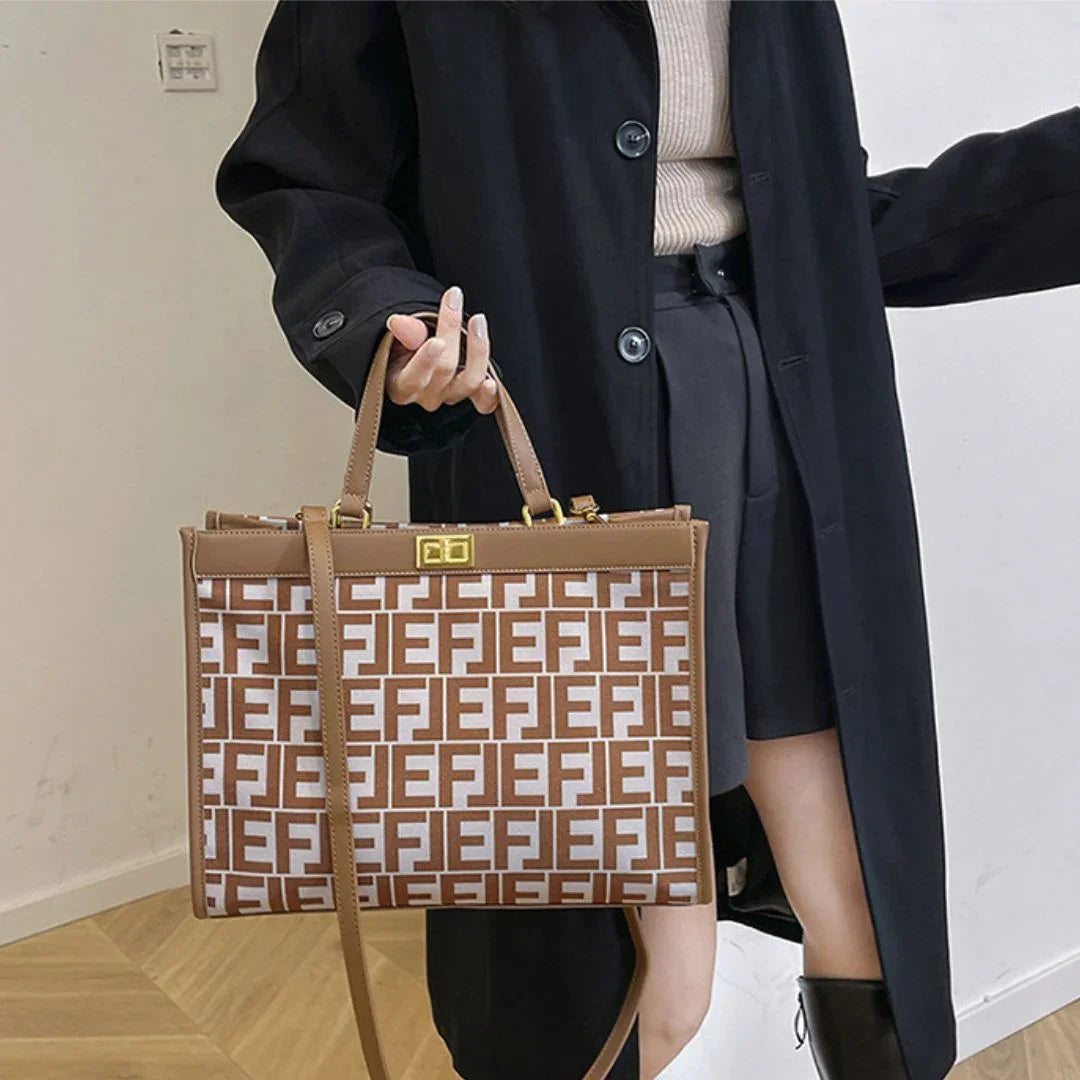 Woman in black coat holding large brown Fendi tote bag with monogram print indoors