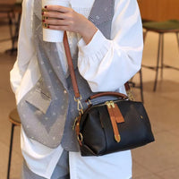Woman holding coffee cup, wearing plaid vest and white blouse, carrying black leather handbag