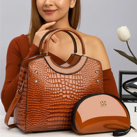 Woman with brown crocodile texture handbag and matching glossy purse on table