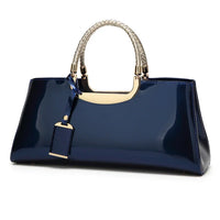 Glossy navy blue handbag with gold accents and braided handles on white background