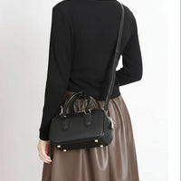 Woman wearing a black crossbody bag and brown skirt, stylish minimalist fashion