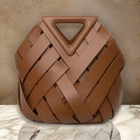 Brown woven leather handbag with triangle handle on marble surface