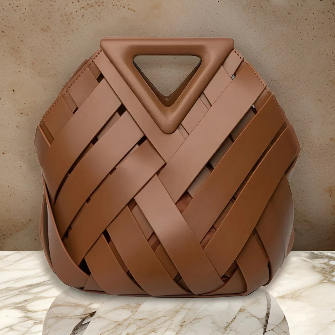 Brown woven leather handbag with triangle handle on marble surface