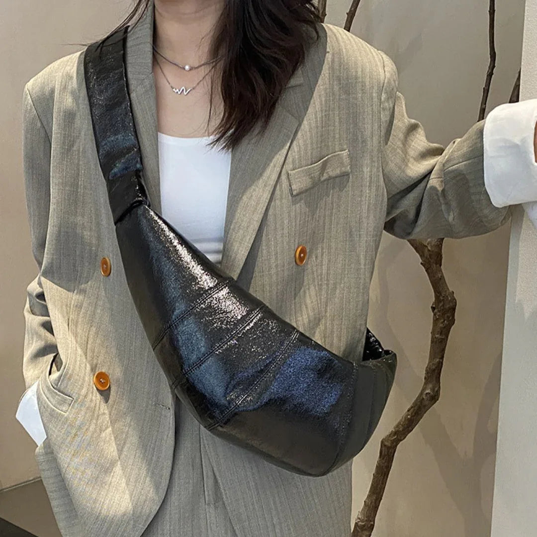 Woman in beige blazer with black leather crossbody bag and layered necklaces
