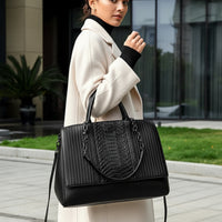 Woman in beige coat carrying black leather tote bag with textured design outdoors