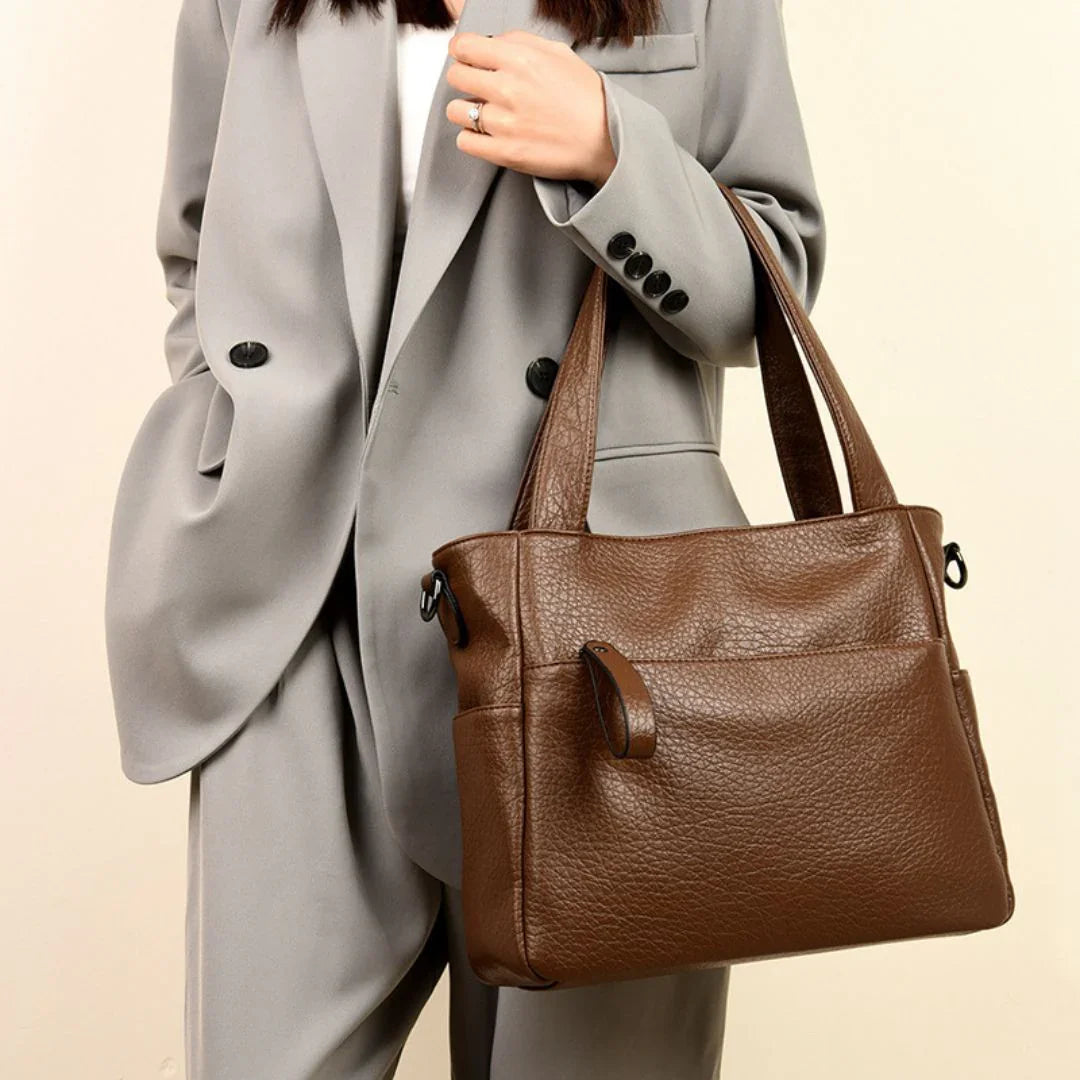 Woman in grey suit holding brown leather tote bag