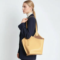 Woman in navy blazer carrying large yellow leather tote bag on shoulder