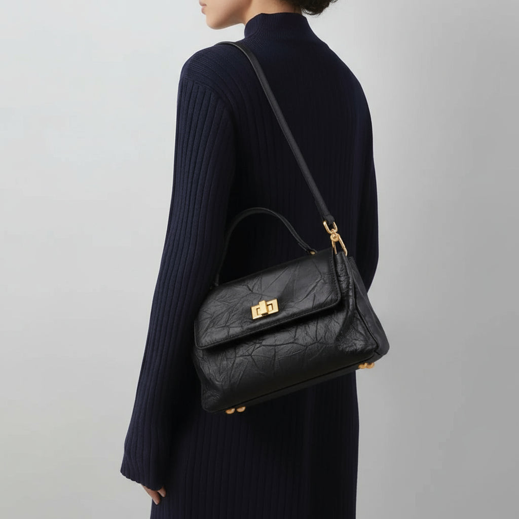 Woman in navy ribbed dress carrying black leather shoulder bag with gold hardware