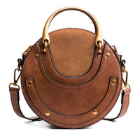 Brown round leather handbag with gold handles and a detachable crossbody strap
