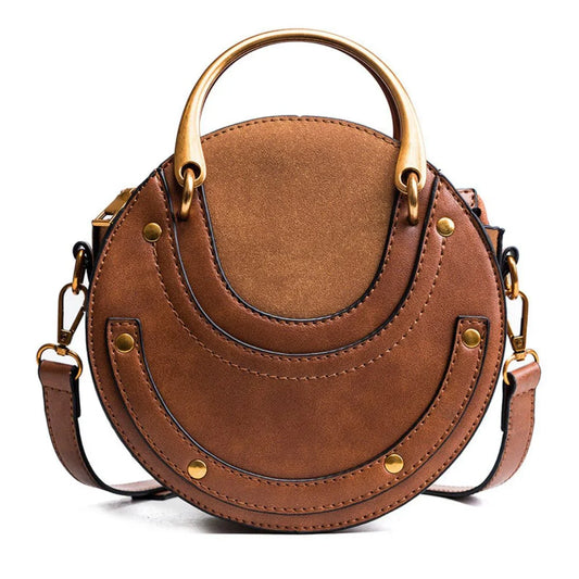 Brown round leather handbag with gold handles and a detachable crossbody strap