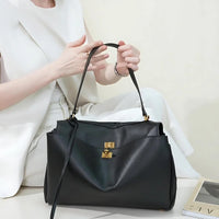 Woman in white suit holding elegant black leather handbag with gold hardware