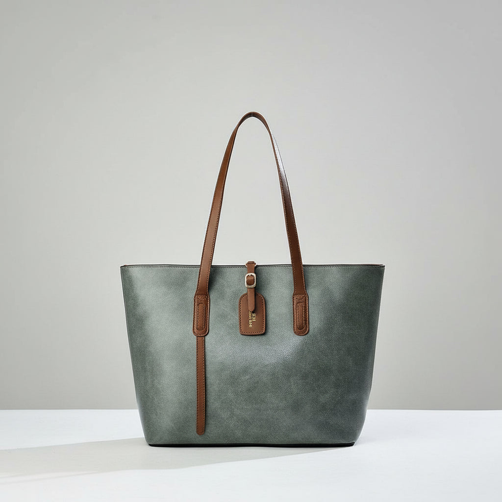Gray leather tote bag with brown handles and tag on a white surface