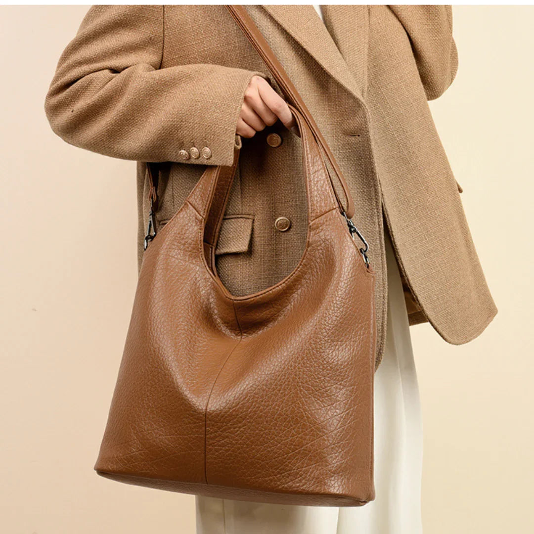 Woman wearing tan blazer holding large brown leather tote bag