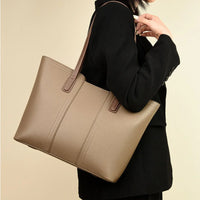 Woman in black blazer carrying taupe leather tote bag with brown handles