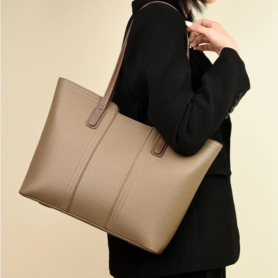 Woman in black blazer carrying taupe leather tote bag with brown handles