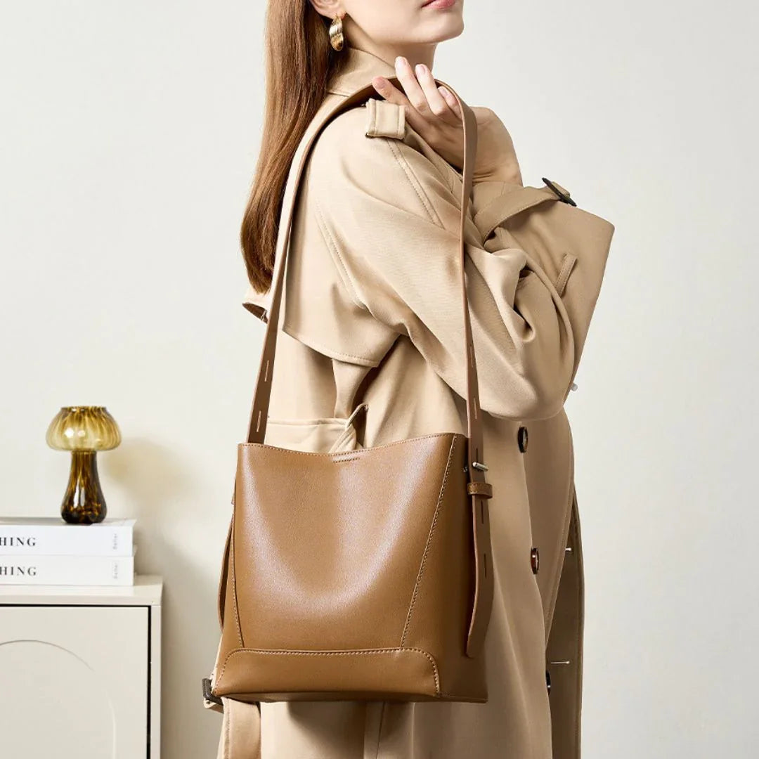 Woman in beige trench coat carrying a brown leather shoulder bag