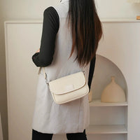 Woman wearing a cream textured crossbody bag in a modern minimalist room