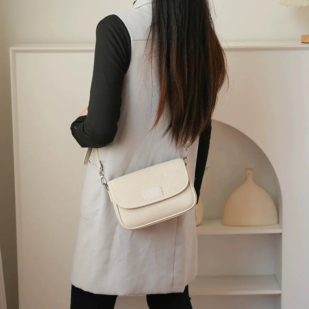 Woman wearing a cream textured crossbody bag in a modern minimalist room